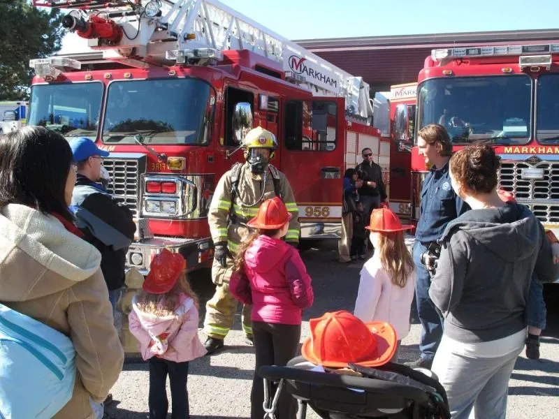 firefighter in front of aerial fire truck talking to visitors of the fire station open house