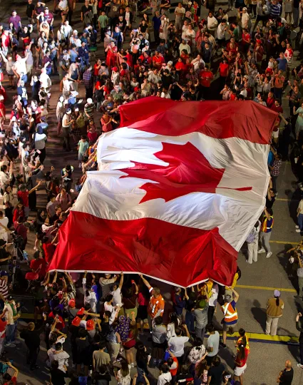Canadian flag over crowd at event.
